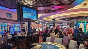 Un casino con numerosas máquinas tragamonedas, una mesa de ruleta y una zona de bar.