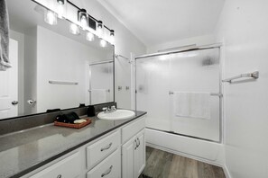 A bathroom with a white sink, a large mirror, and a glass shower enclosure. - Luxe & Spacious Retreat - Steps to Beach Game Room (Encinitas)