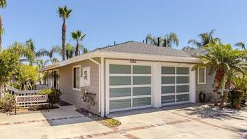 A single-story house with a garage, surrounded by palm trees and a small garden.