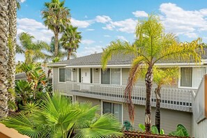 A two-story house with a balcony, surrounded by various tropical plants. - Luxe & Spacious Retreat - Steps to Beach Game Room (Encinitas)