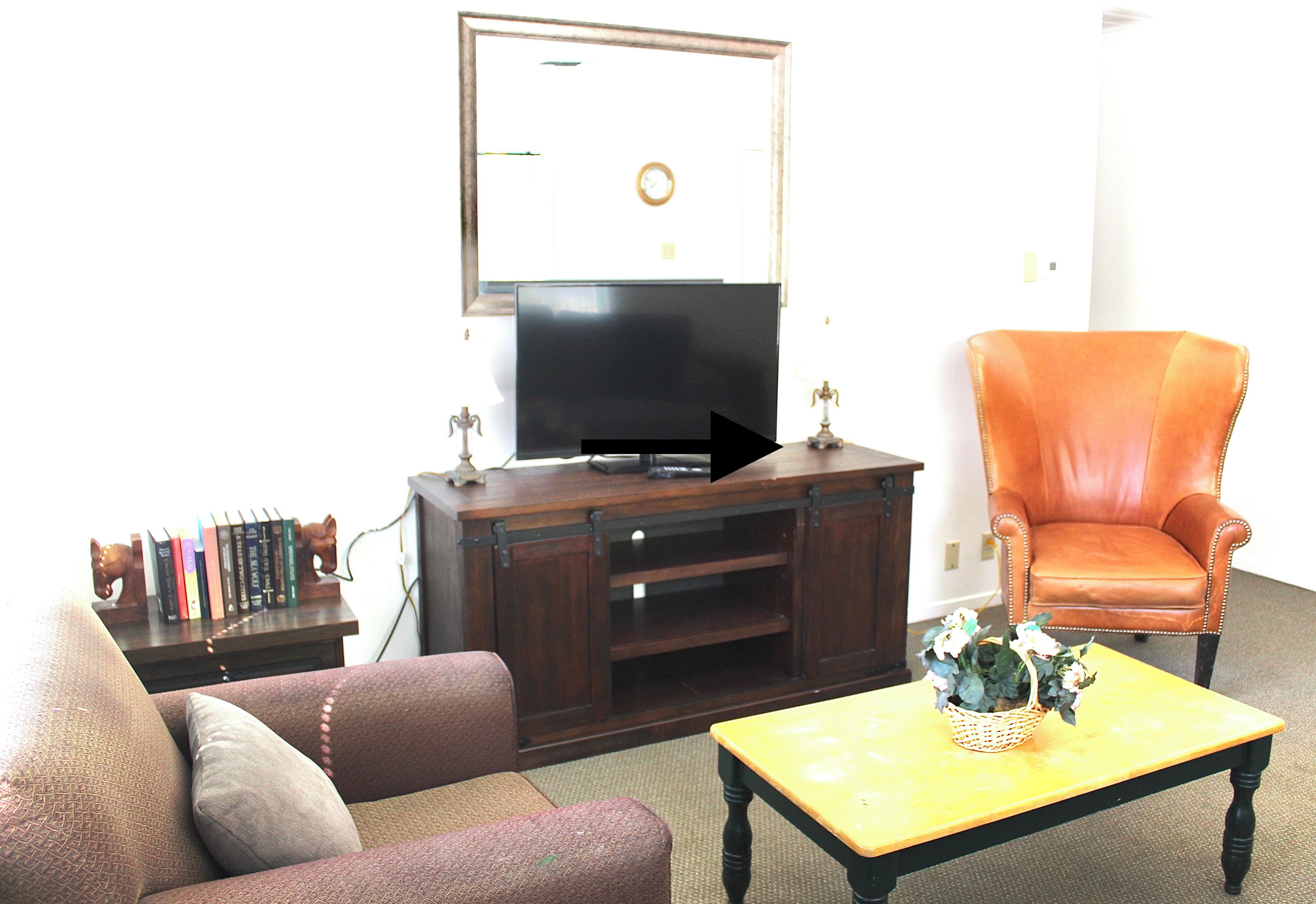 A living room with a television, a sofa, an armchair, a coffee table, and a bookshelf.