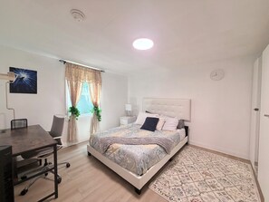 A bedroom with a bed, desk, chair, and a window with curtains. - 
Modern One bedroom Guest House with WiFi, AC, Charming Patio, near Culver City, (Los Angeles)