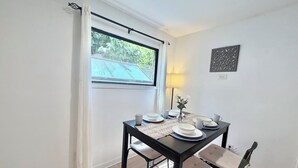 Een eetruimte met een tafel voor vier personen, een lamp en een decoratief object aan de muur.
