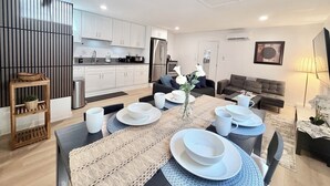 Een moderne keuken met witte kastjes, een roestvrijstalen koelkast, en een eethoek met een ronde tafel gedekt voor vier personen.