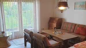 A cozy room with a wooden ceiling, a dining table with chairs, a sofa, and a hanging lamp. - Landhaus Münz, quiet vacation apartment near Hopfen am See near Füssen (Hopferau)
