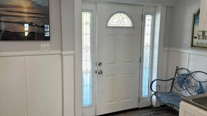 A clean, well-lit entryway with a white door, a glass window, and a bench.