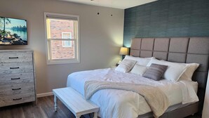 A bedroom with a bed, a bench, a dresser, a window, and a ceiling fan. - Escape to Spicer and enjoy stunning lake views from this comfortable 2-bedroom! (Spicer)