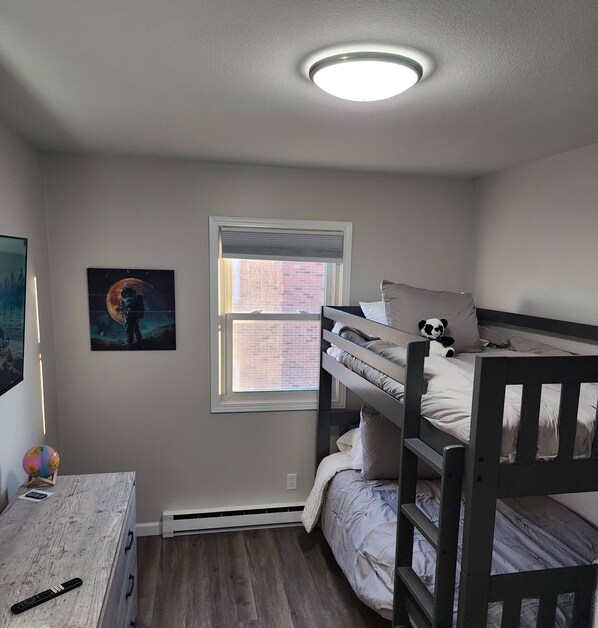 Une chambre avec un lit superposé, une fenêtre, un tableau et un globe terrestre posé sur une table.