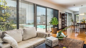 Un salon moderne avec un canapé, une table basse et une grande fenêtre équipée de stores.