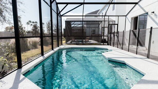 A swimming pool with a clear view of the surrounding area, including a house and trees. - Grand Resort Home in Resort with Pool (Kissimmee)