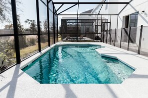 A swimming pool with a clear view of the surrounding area, including a house and trees. - Grand Resort Home in Resort with Pool (Kissimmee)