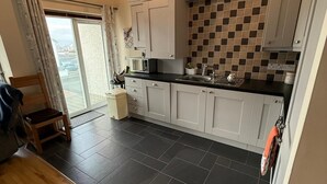 A modern kitchen with grey cabinets, a black tiled backsplash, and a wooden floor.