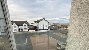 A balcony with a view of a residential area, including houses and a road.