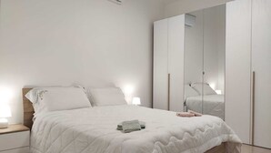 Een slaapkamer met een bed, nachtkastjes, een kledingkast en een spiegel.