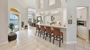 A spacious kitchen with a central island, bar stools, and a view of the outdoors. - Sunset view villa (Cape Coral)