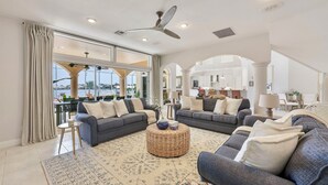 A spacious living room with two sofas, a coffee table, and a view of the city through large windows. - Sunset view villa (Cape Coral)