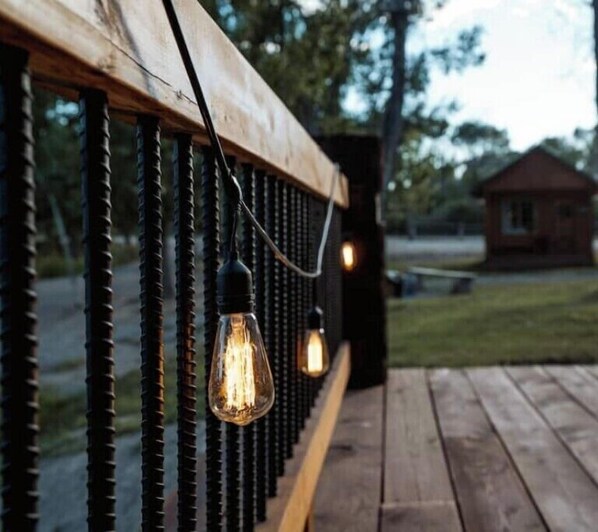 Una terraza de madera con barandilla y luces colgantes.