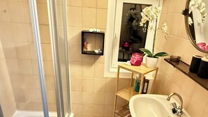 A bathroom with a shower, sink, and a window with a potted orchid. - House Bernstein, Apartman 3 (Haus im Ennstal)