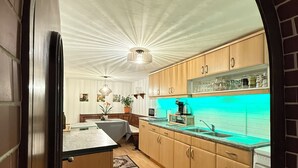A modern kitchen with wooden cabinets, a central island, and a built-in oven. - House Bernstein, Apartman 3 (Haus im Ennstal)
