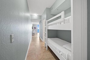 A narrow hallway with bunk beds on one side and a door leading to another room.