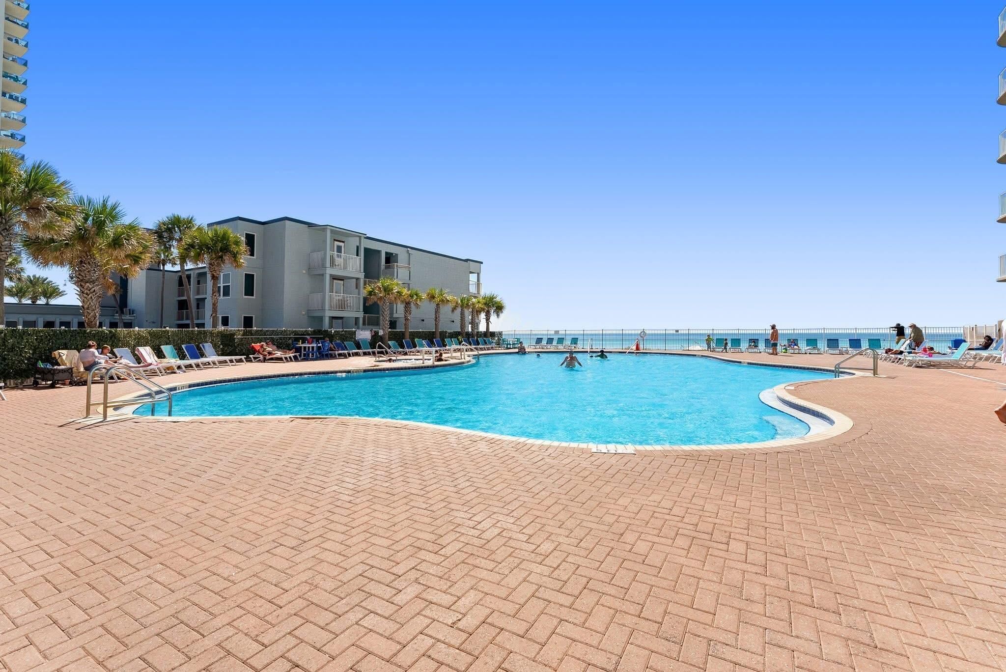 A swimming pool area with lounge chairs and a building in the background.