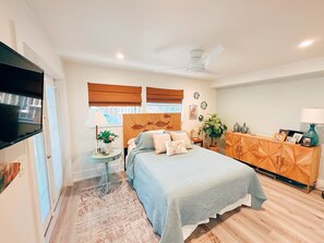 Relax in this inviting bedroom with a large bed, a television, and a wooden cabinet.