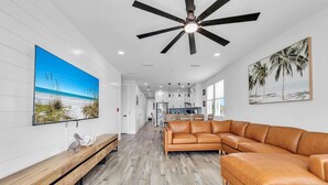A spacious living area with a large leather sofa, a wooden bench, and a ceiling fan. - Golden Seashell East (Panama City Beach)