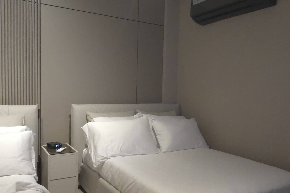 A modern bedroom with a large bed, two bedside tables, a nightstand, and a ceiling light.