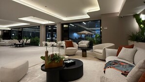 A spacious living area with modern furniture, a round coffee table, and a large window offering a view of the outdoors. - La Résidence Panamá (Panama City)