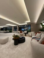 A spacious living area with modern furniture, a round coffee table, and a large window offering a view of the outdoors.