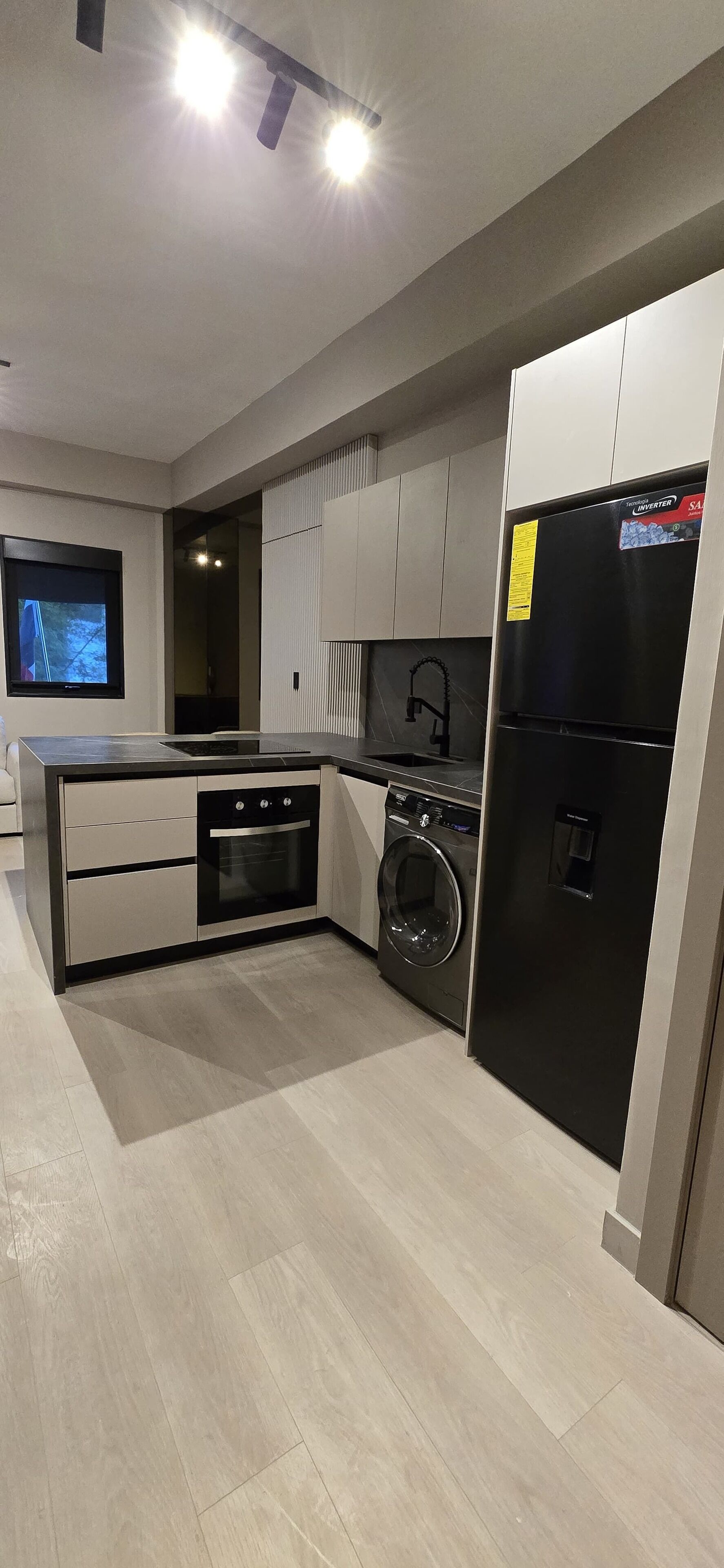 A modern kitchen with a built-in oven, washing machine, and refrigerator.
