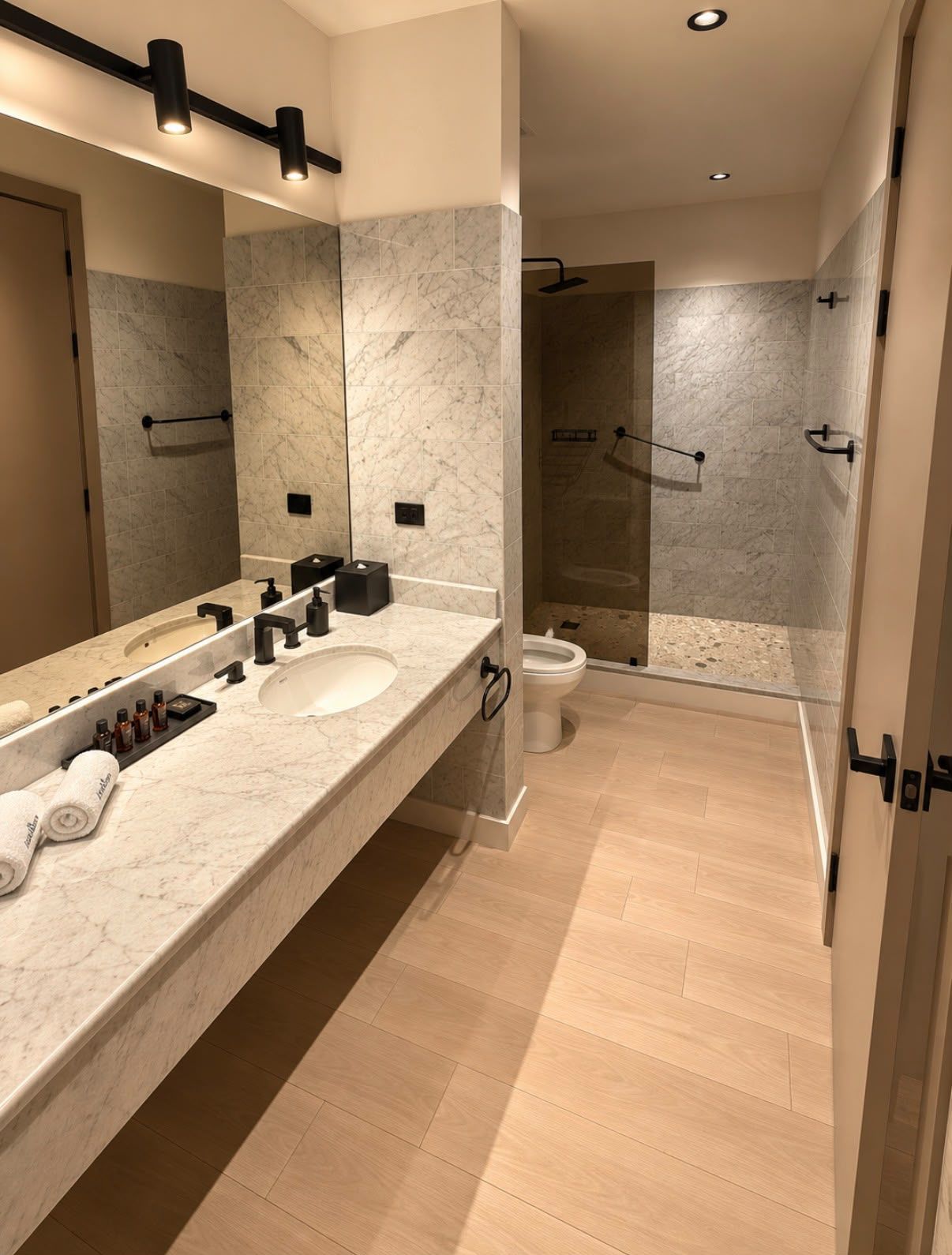 A modern bathroom with a marble vanity, a large mirror, a shower with glass doors, and a toilet.