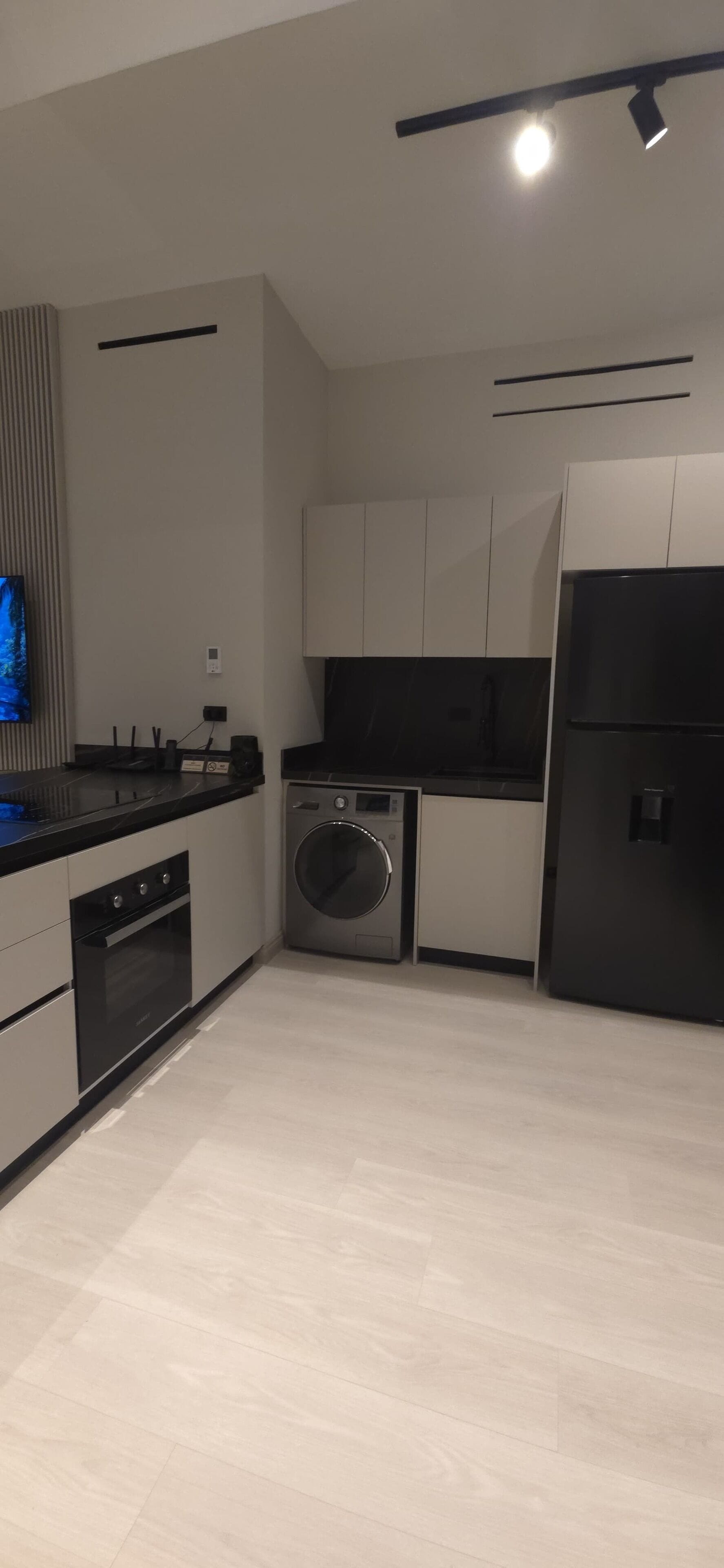 Una cucina moderna con forno a incasso, lavatrice e frigorifero.
