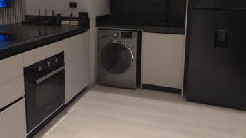 Una cucina moderna con forno a incasso, lavatrice e frigorifero.