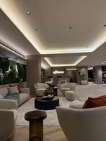 A modern hotel lobby with sofas, a coffee table, and a reception desk.