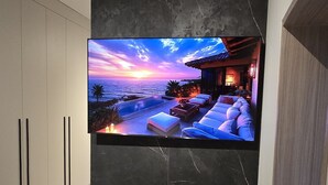 A bedroom with a large TV mounted on a marble wall, a bed, and a wooden cabinet. - La Résidence Panamá (Panama City)