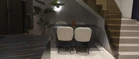 En modern inredning med en trappa, en matplats med två stolar och en köksbänk.