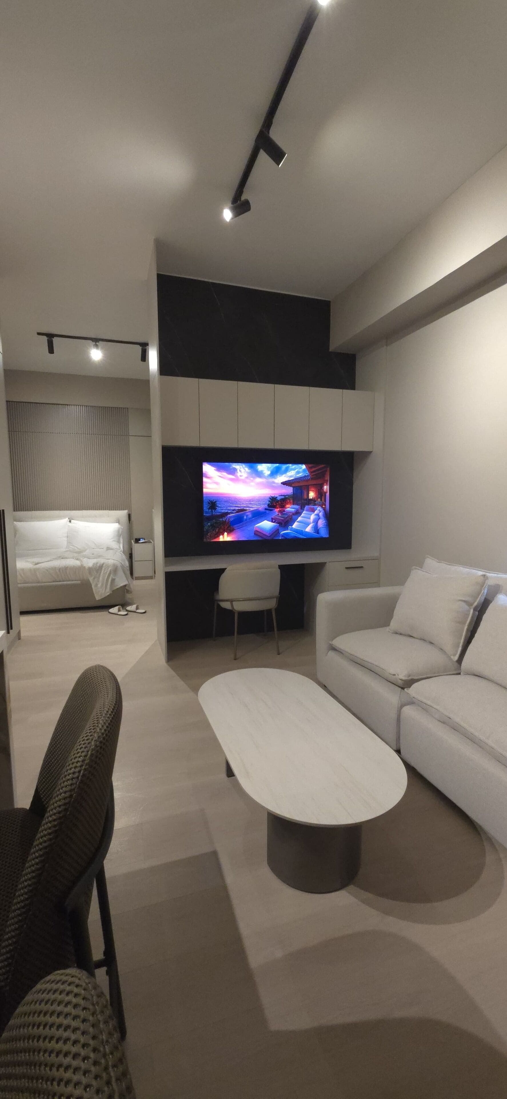 A modern living room with a flat-screen TV, a sofa, a coffee table, and a dining area.