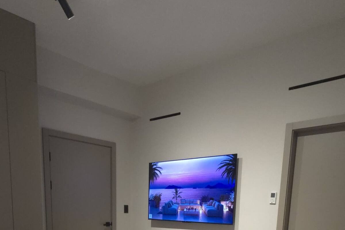 A bedroom with a bed, a TV mounted on the wall, and a ceiling light fixture.
