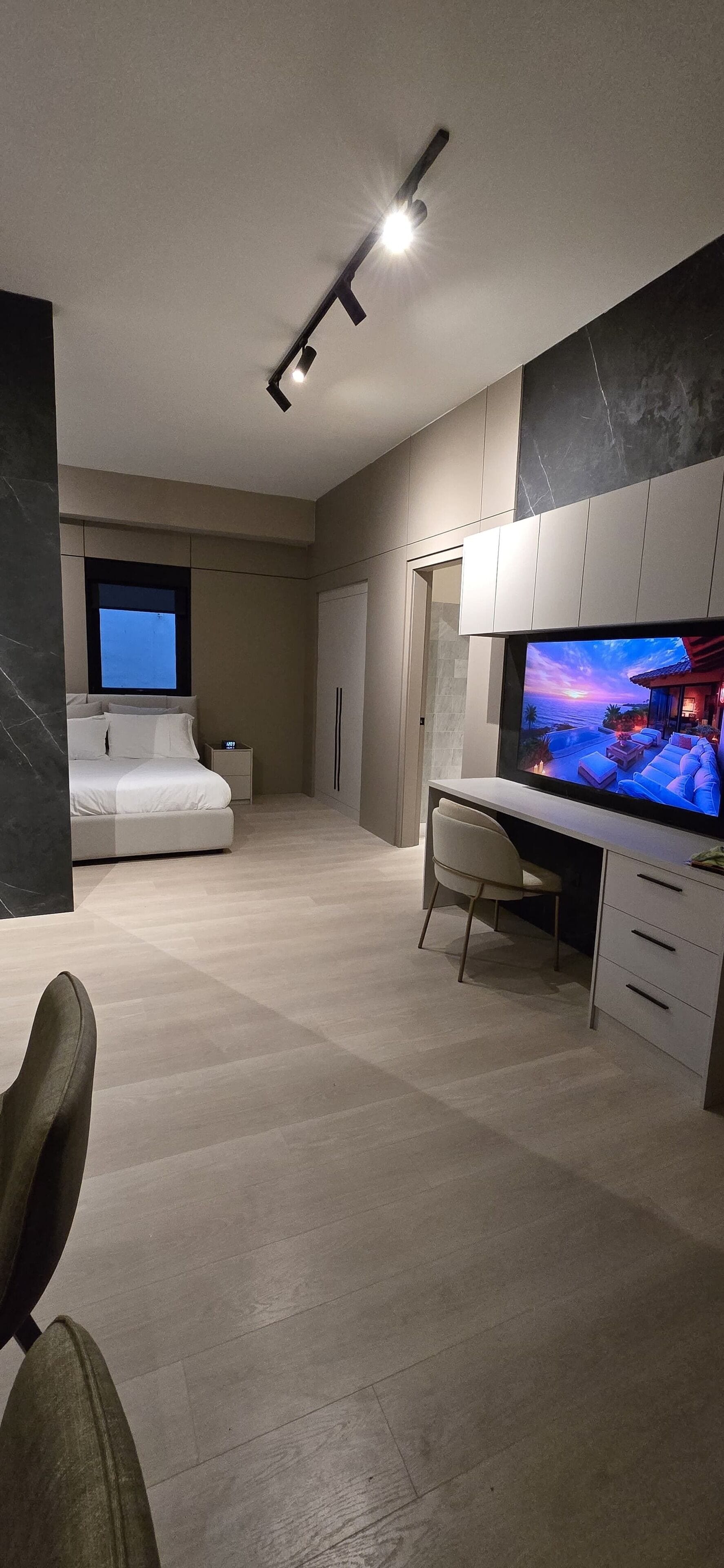 Un dormitorio moderno con cama, escritorio y televisor.
