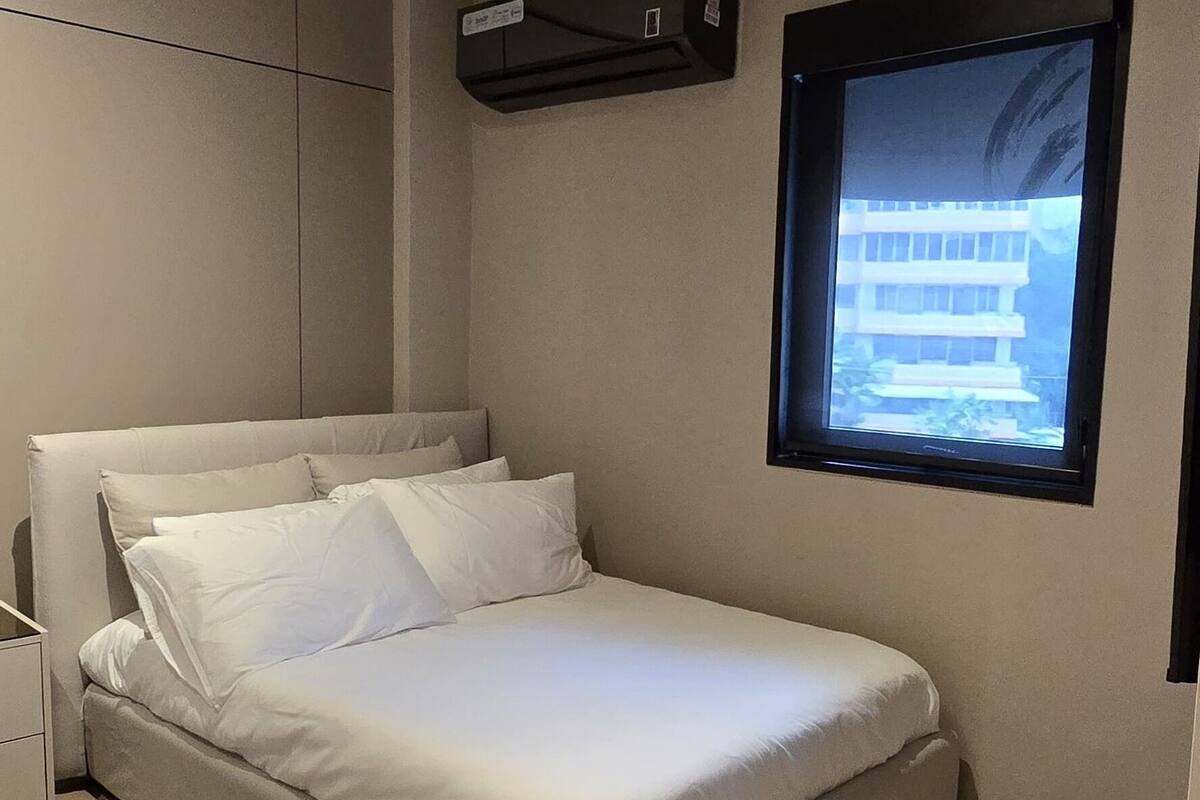 A modern bedroom with a bed, a nightstand, a wall-mounted TV, and a ceiling light.