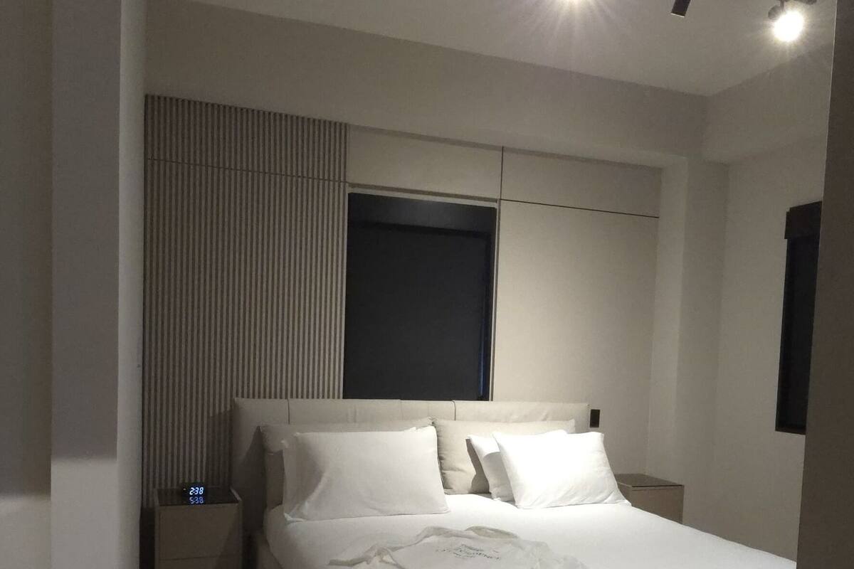 A modern bedroom with a large bed, bedside tables, and a nightstand.