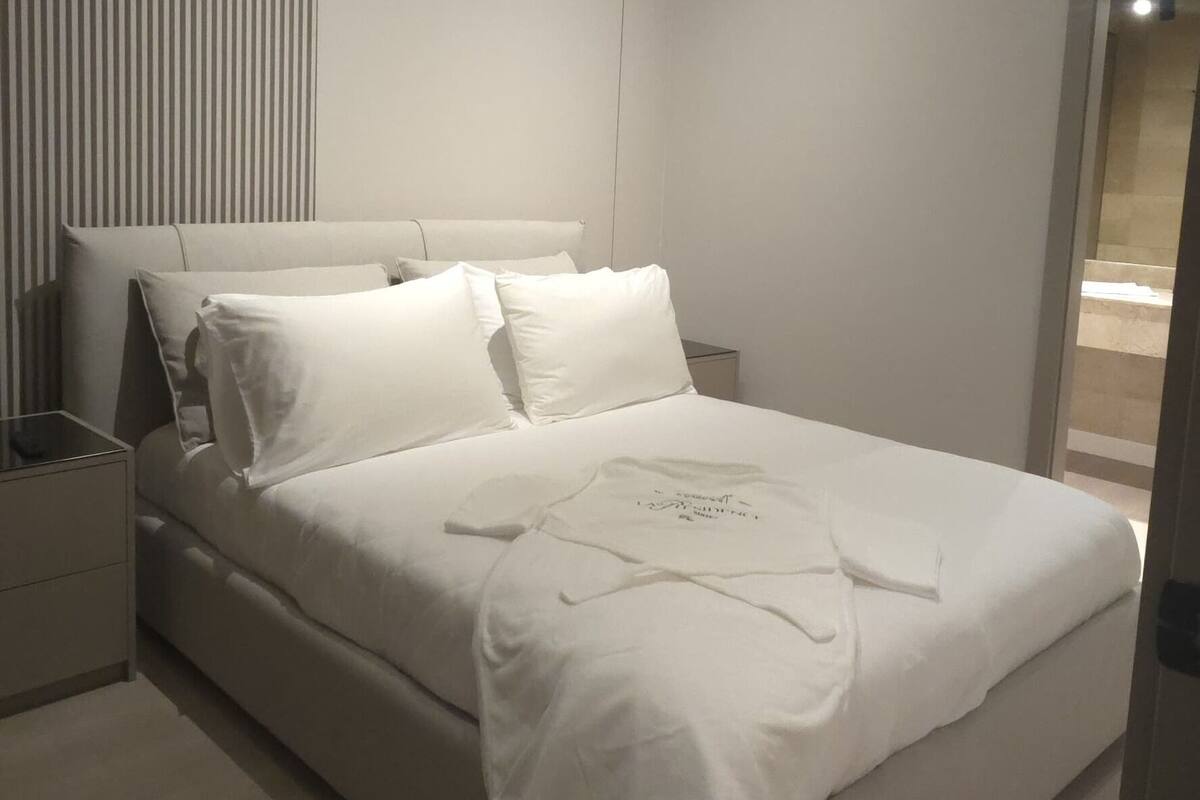 A modern bedroom with a large bed, a nightstand, and a ceiling light fixture.