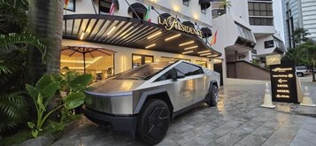 A modern building with a sign reading "LA RESIDENCE" and a car parked in front.