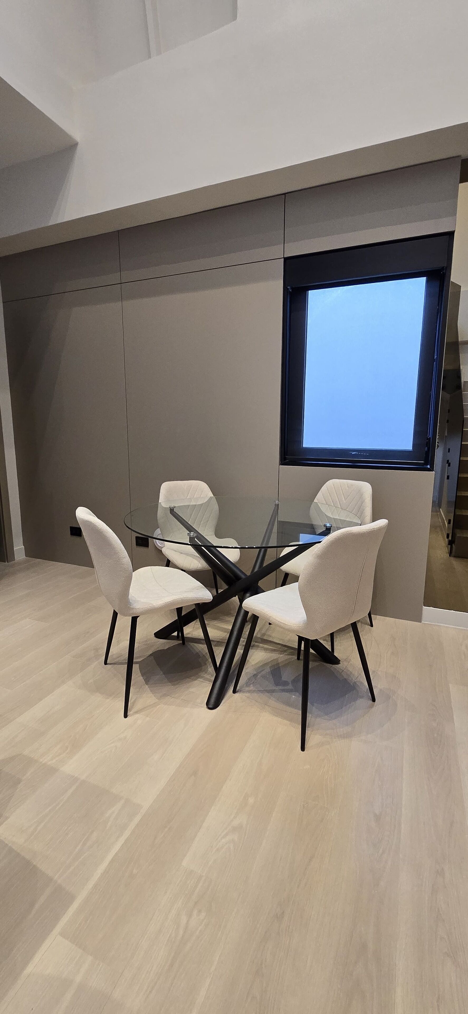Una sala de reuniones moderna con una mesa de vidrio, sillas blancas y un ventanal con vistas.
