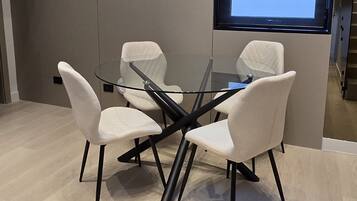 Una sala de reuniones moderna con una mesa de vidrio, sillas blancas y un ventanal con vistas.