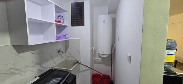 A compact kitchen with a built-in washing machine, a water heater, and a small sink.