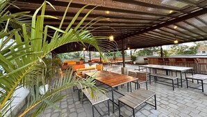 An outdoor patio area with wooden tables and benches, surrounded by potted plants. - A vibrant and connected hub blending urban living, green spaces, and convenience (Nairobi)