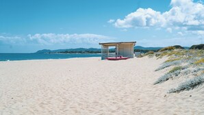 A beach with a small pavilion and a boat. - Velis - art & hospitality (Posada)