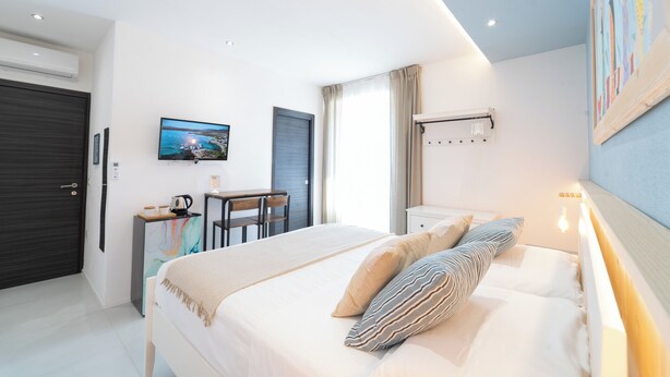 A modern bedroom with a bed, bedside table, and a desk with a chair. - Velis - art & hospitality (Posada)